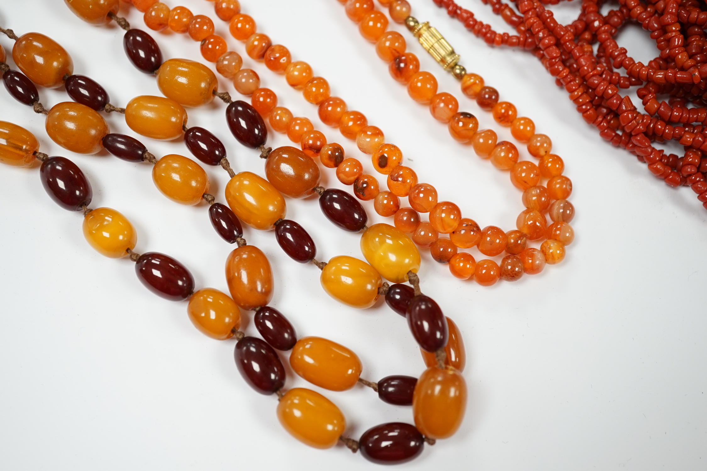 A single strand amber and simulated cherry amber bead necklace, 72cm, gross weight 33 grams, together with two other necklaces including agate bead.